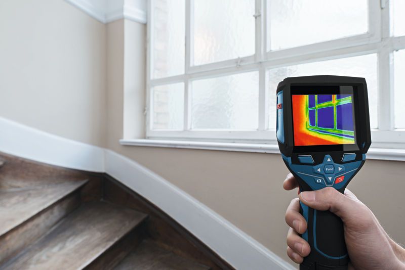 En person undersøker et vindu med Bosch GTC 400 C termokamera.