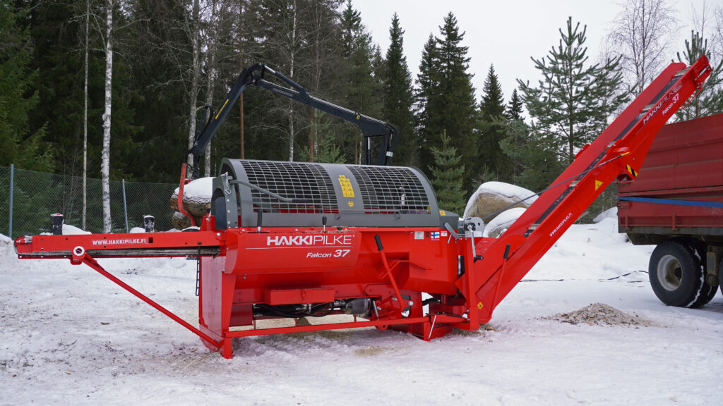 Hakki Pilke Falcon 37 vedmaskin oppstilt med uttransportør ved en tilhenger i snø.